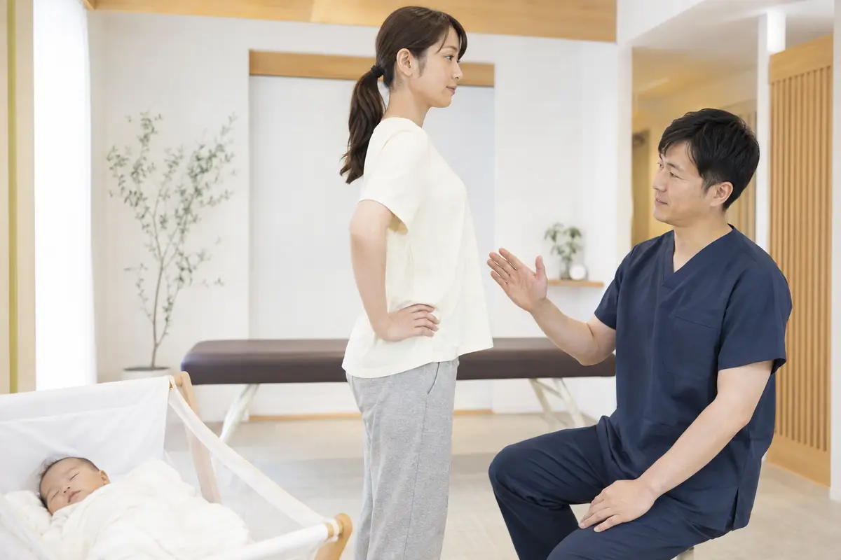 赤ちゃん連れで産後の姿勢を確認する整骨院での相談風景