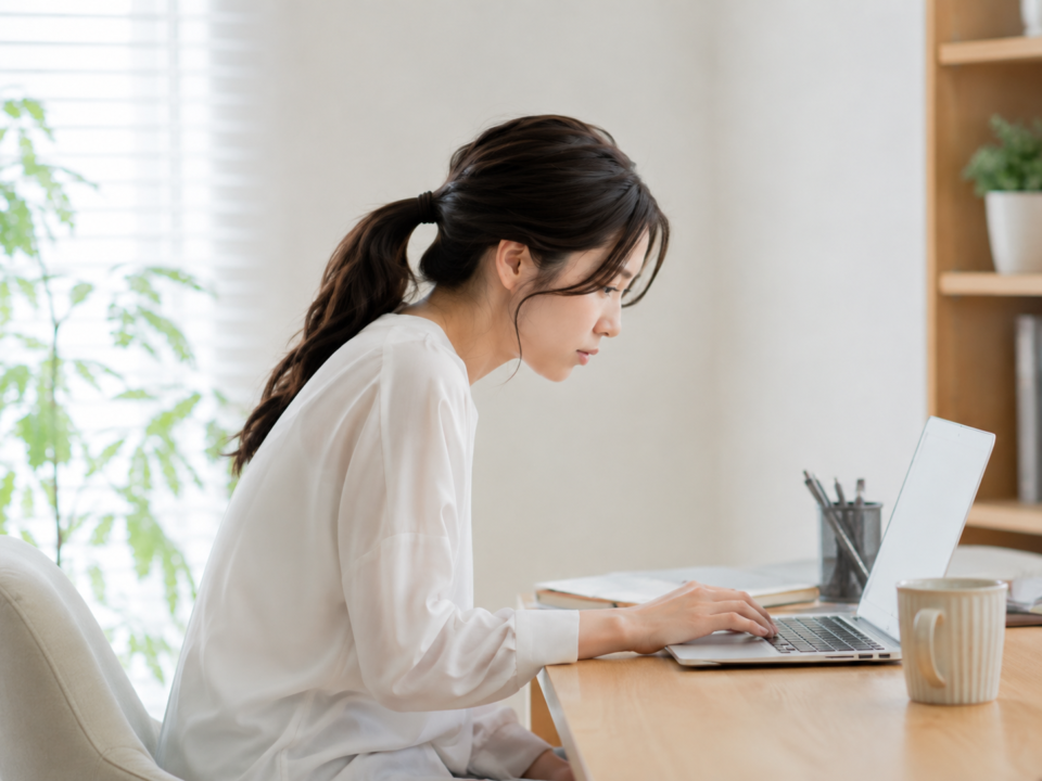 前かがみ姿勢でパソコン作業をする女性のデスクワーク姿勢