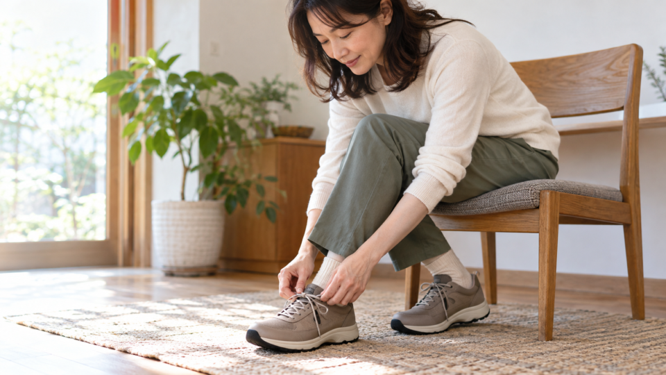 椅子に座って靴のひもと足元を確認する女性