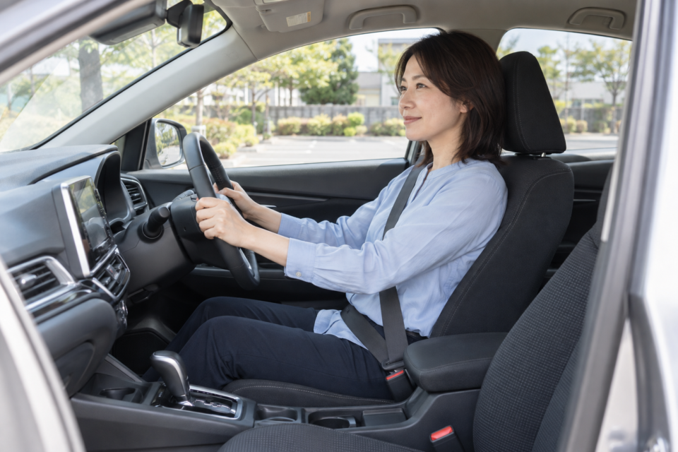安全に駐車した車の運転席でシートベルトを着けて座る女性