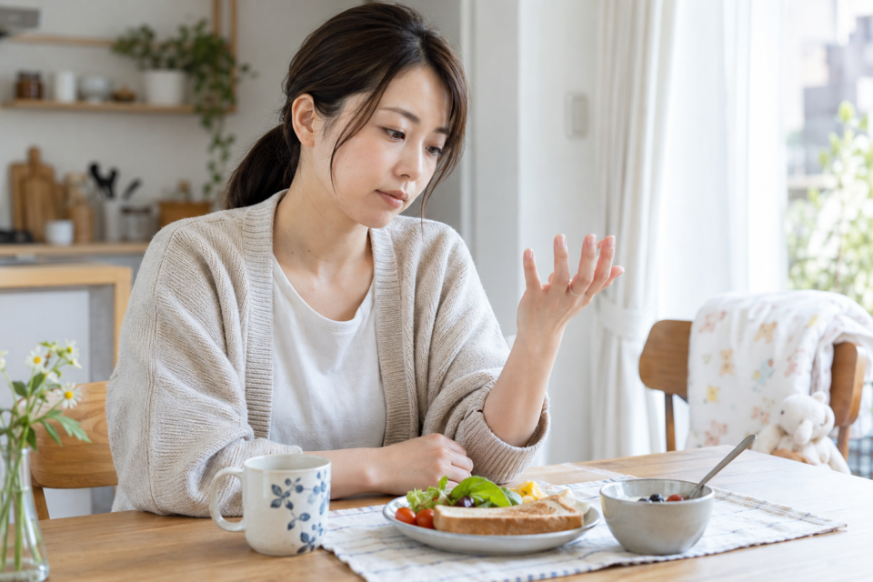 食卓で自分の手を確認する女性