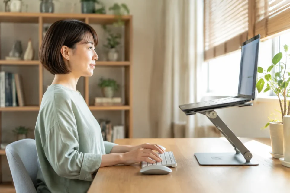 ノートパソコンを台に載せ外付けキーボードを使う女性