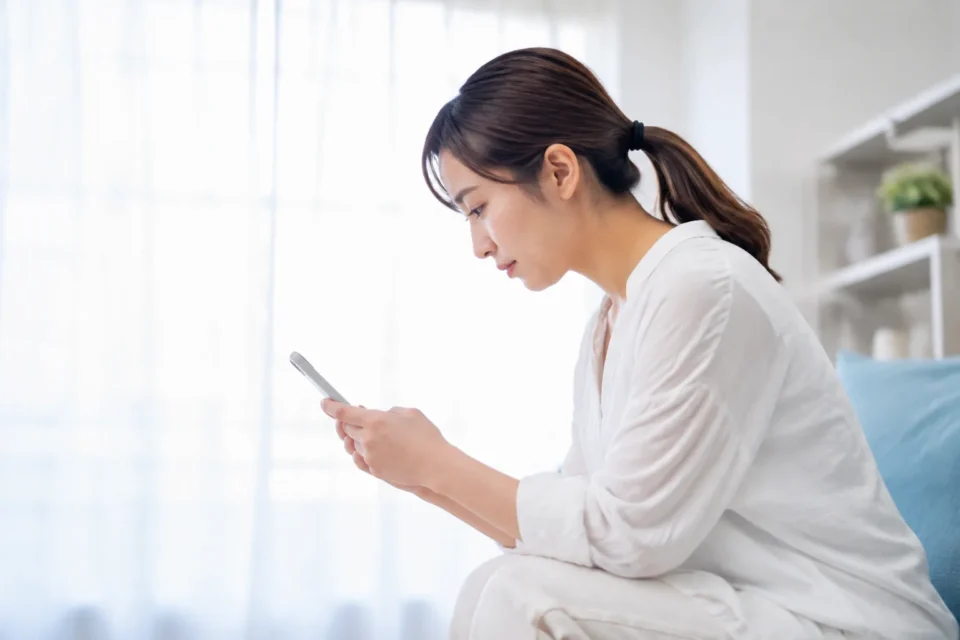 スマートフォンを低い位置で見る女性の首の姿勢