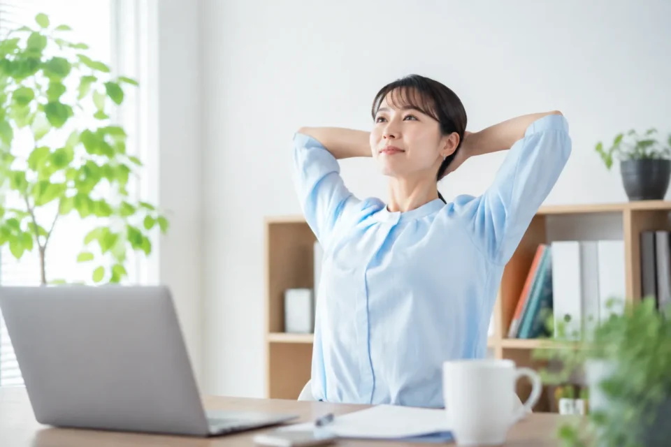 デスクワークの合間に肩と背中をやさしく動かす女性