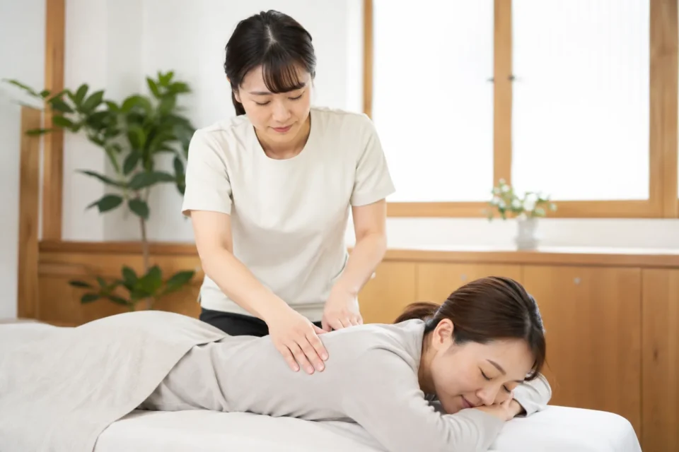 女性施術者が肩甲骨周辺へやさしく施術する様子