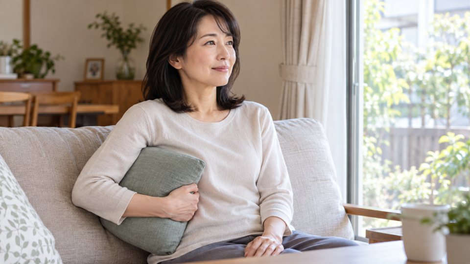 座った姿勢で胸の側面に柔らかいクッションを添える成人女性の説明用イメージ