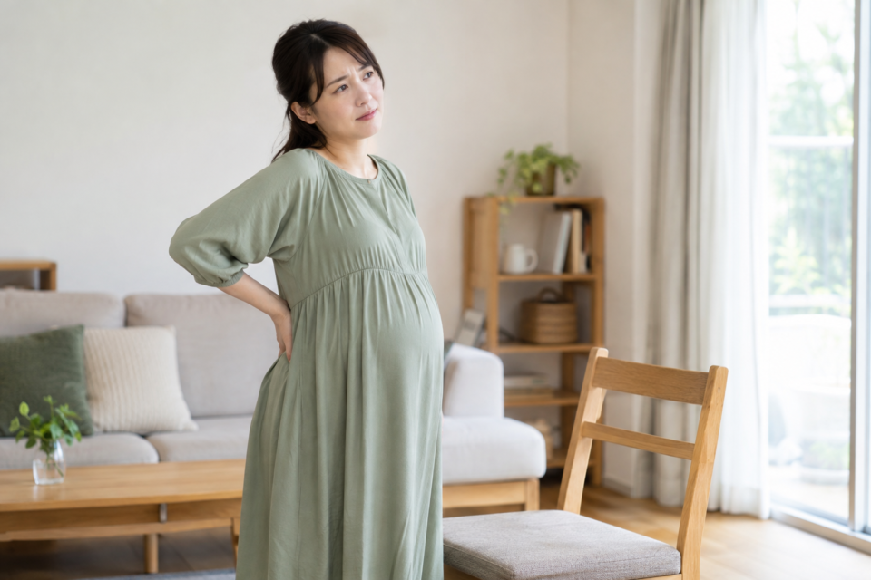腰に手を添えて体の状態を確かめる妊娠中の女性